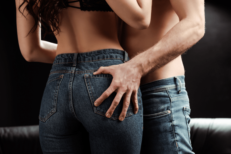 Shirtless man with hand on butt of sexy girlfriend